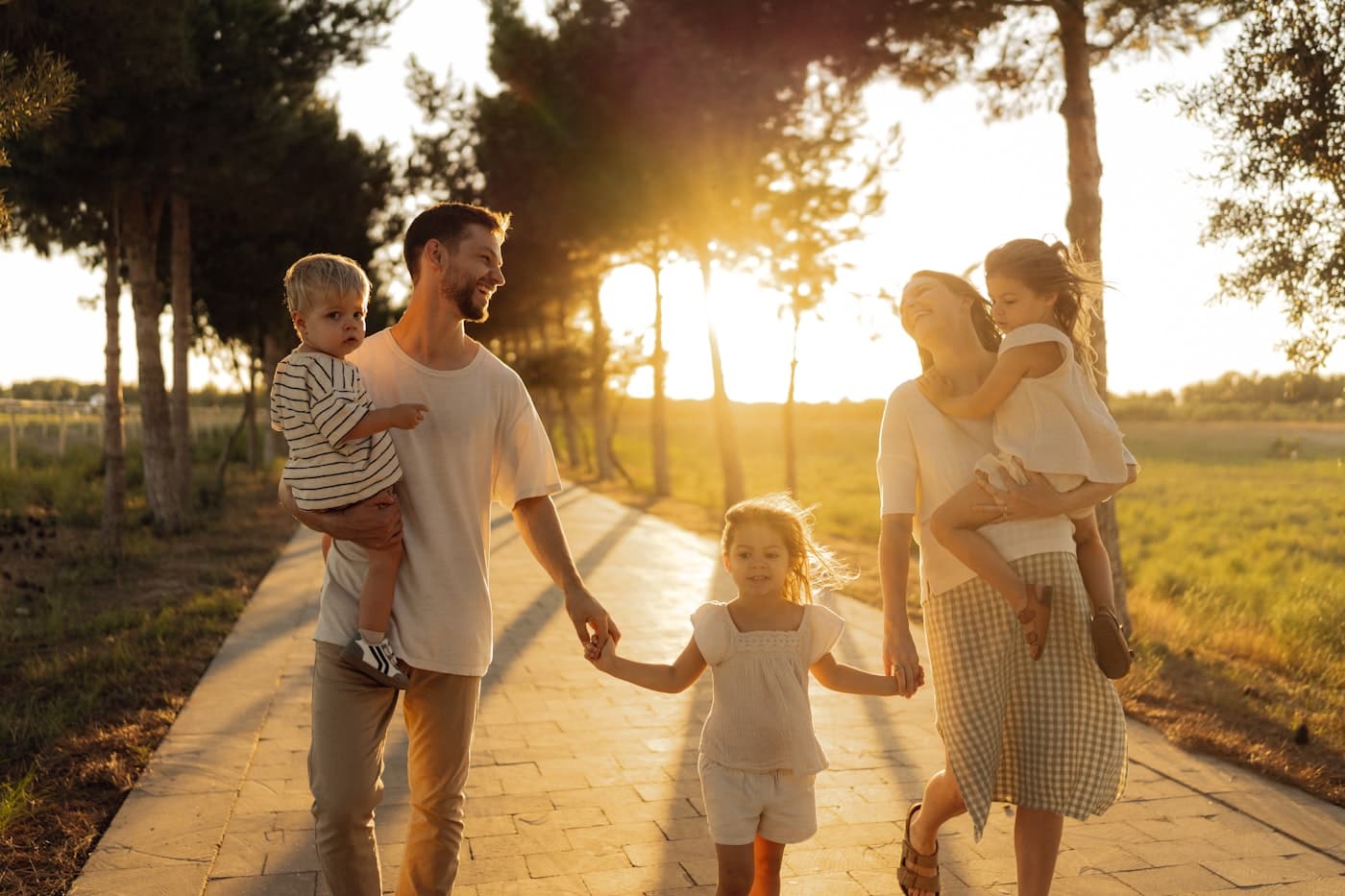A family walking a tree-lined path at sunset